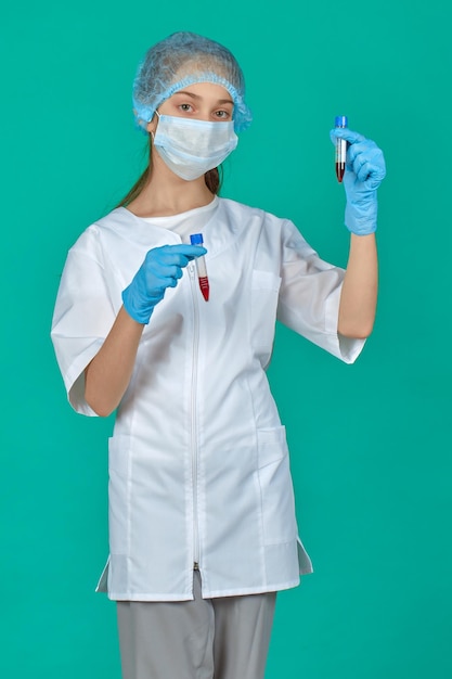 a girl dressed in a doctor's uniform in test tubes with blood in her hands on a green background