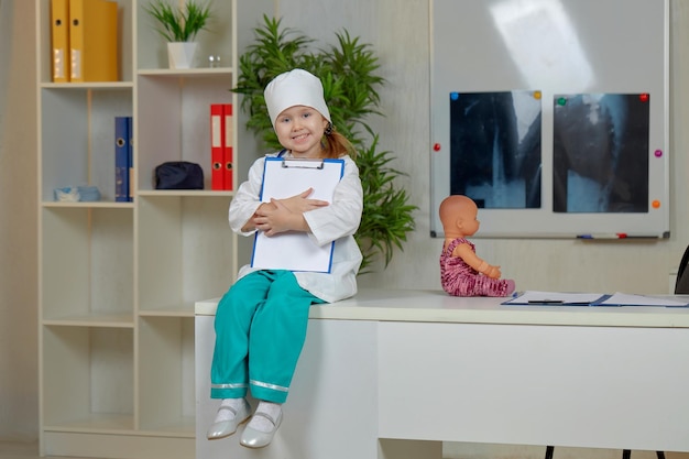 A girl dressed in a doctors uniform is sitting on a desktop office