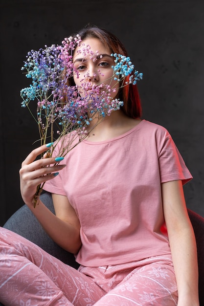 Foto ragazza vestita in pigiama rosa con in mano un mazzo di fiori secchi