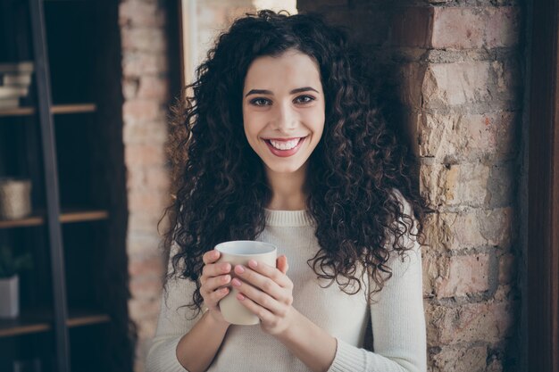 Ragazza che beve caffè nella sala interna in stile moderno loft industriale in mattoni