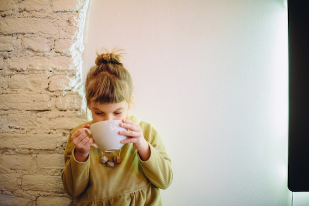 Foto una ragazza che beve da una tazza grande