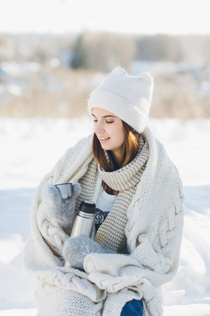 Girl drinking hot tea from a thermos 