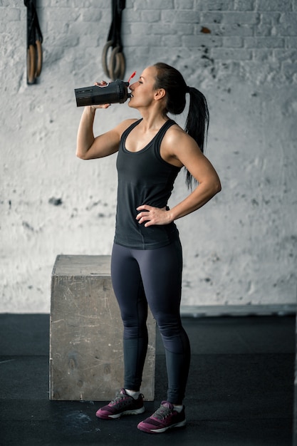 Acqua potabile della ragazza in palestra dopo l'allenamento