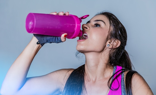 Girl drinking water in gym after workout.