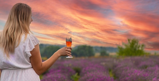 Девушка пьет шампанское в лавандовом поле Селективный фокус на природе