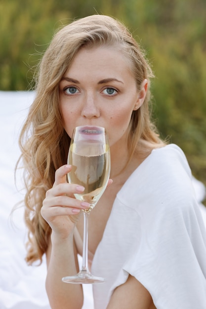 Girl drinks champagne in the summer in nature