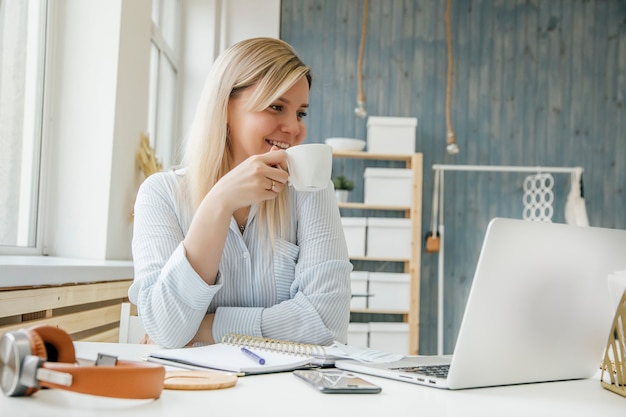 a girl drinks coffee at her desk