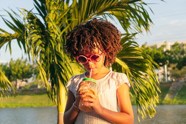 Girl drinks juice from bottle through straw while walking outdoors