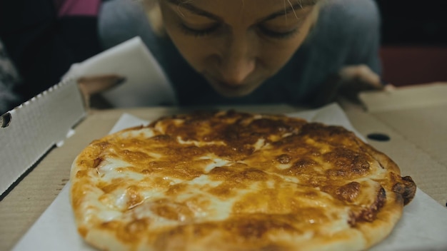女の子はピザチーズ4を食べる若い女性の口のクローズアップ貪欲にピザを食べて屋外レストランで噛むジャンクフードオープンボックスからピザ