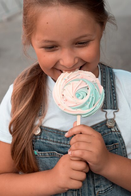 girl eating big sweet meringue on stick