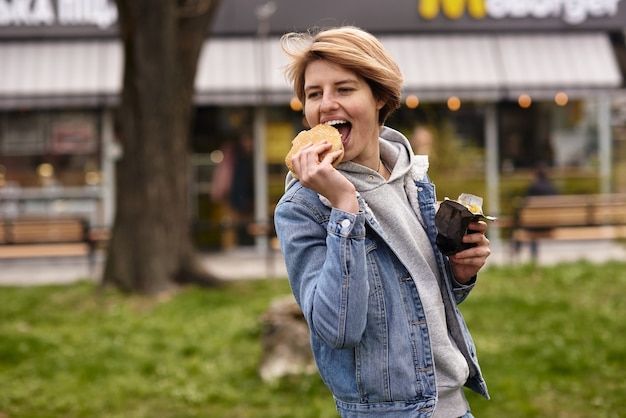 Girl eating a burger with fast food