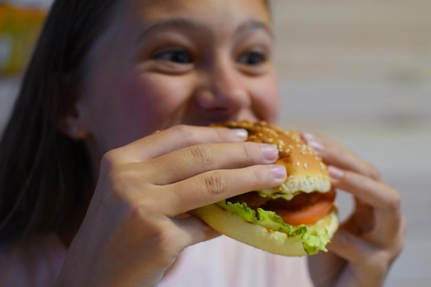 Girl eating delicious fast food hamburger with fries.