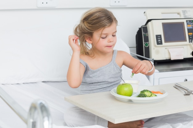 Girl eating healthy food in hospital bed