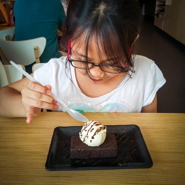 写真 テーブルでアイスクリームを食べている女の子