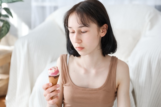 自宅でリビングルームの背景とアイスクリームを食べる女の子。子供の女の子は、食べることと空腹の概念を楽しんでいます。