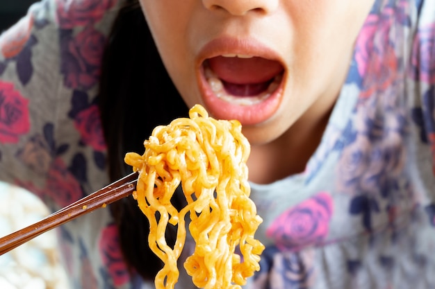 Girl Eating Instant Korea Noodles, She Use Chopstick for Chinese vermicelli into mouth