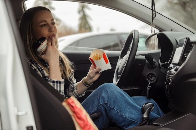 Ragazza che mangia cibo spazzatura in macchina