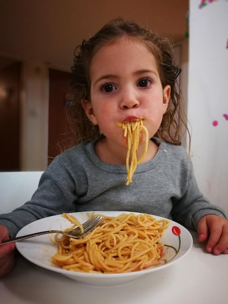 Girl eating spaghetti at table