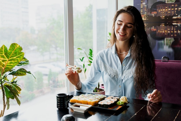 Girl eating sushi in japanese restaurant