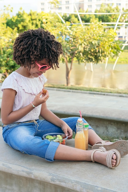 夏に公園に座って野菜を食べる女の子