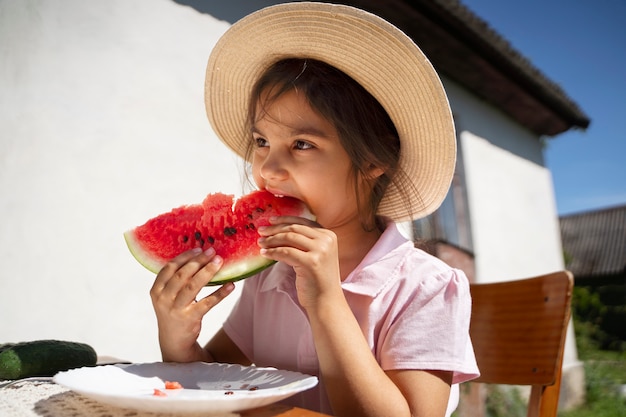 屋外のテーブルでスイカを食べる女の子