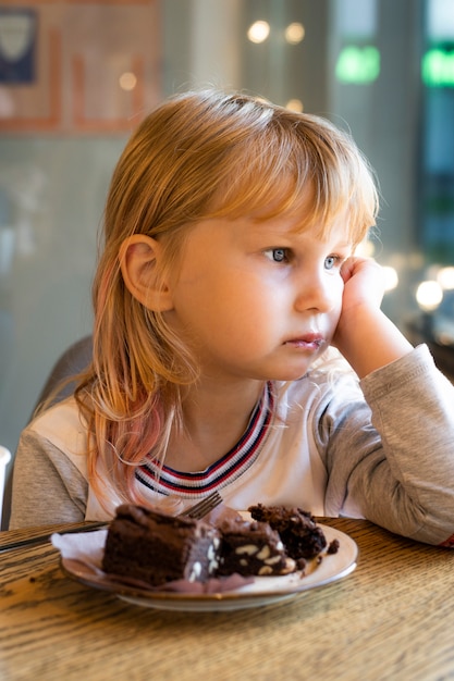 女の子はカフェでデザートにチョコレートケーキを食べる