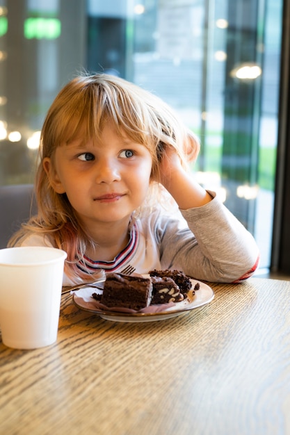 女の子はカフェでデザートにチョコレートケーキを食べる