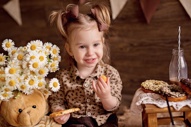 女の子はクッキーを食べ、テディベアを食べさせます。