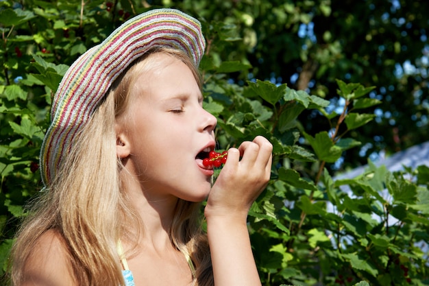 Girl eats red currant in the garden