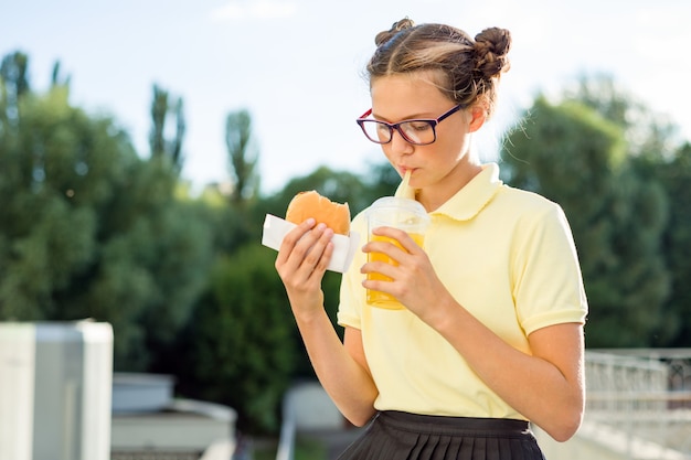 Girl eats sandwich and drinks orange juice