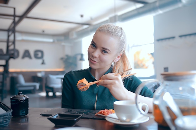 girl eats sushi and rolls in a restaurant / oriental cuisine, Japanese food, young model in a restaurant