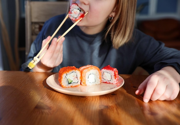 Girl eats sushi rolls at the table