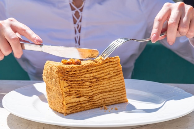 女の子は甘いデザートの層状ケーキを食べる