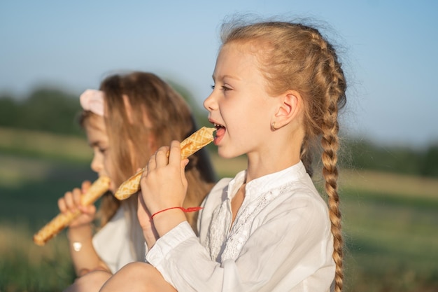 女の子は自然の中でお菓子を食べる 子供たちはお菓子に依存する 2人の姉妹はストローを食べる