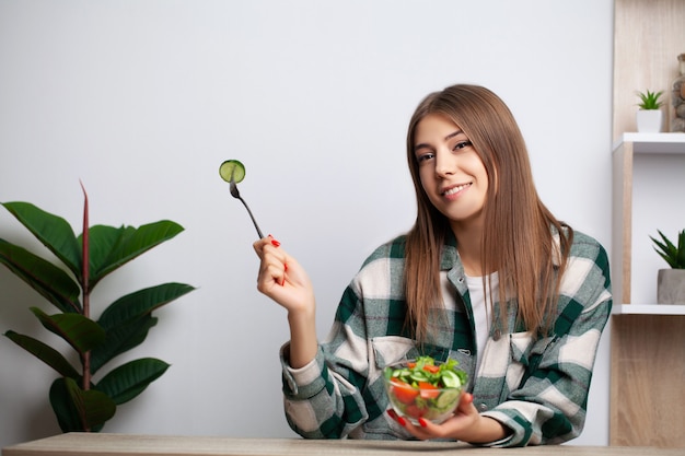 La ragazza mangia insalata di verdure con un sacco di vitamine