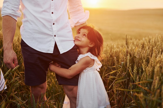 Girl embraces parent Father with daughter spending free time on the field at sunny day time of summer