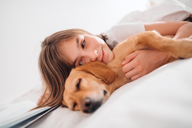 ベッドで犬を抱きしめる少女