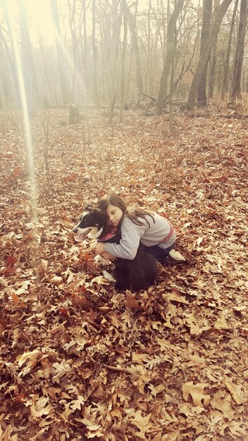 写真 秋の葉の上で犬を抱きしめる少女