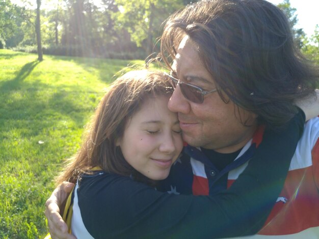 写真 公園のフィールドで父親を抱きしめる少女