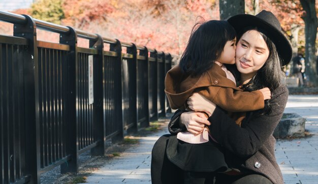 Photo girl embracing woman against railing.