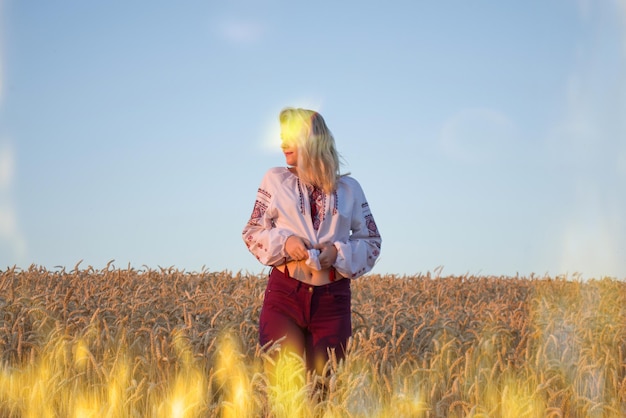 Girl in the embroidered shirt and a wreath on the head on wheat field