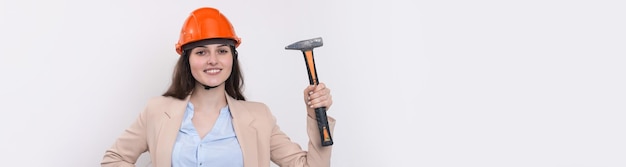 Girl engineer in an orange construction helmet with a hammer on a white background