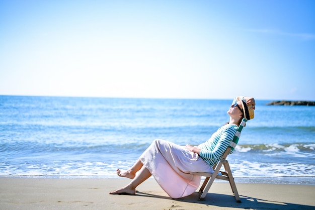 女の子はヴィンテージのデッキチェアで海に沈む夕日をお楽しみください