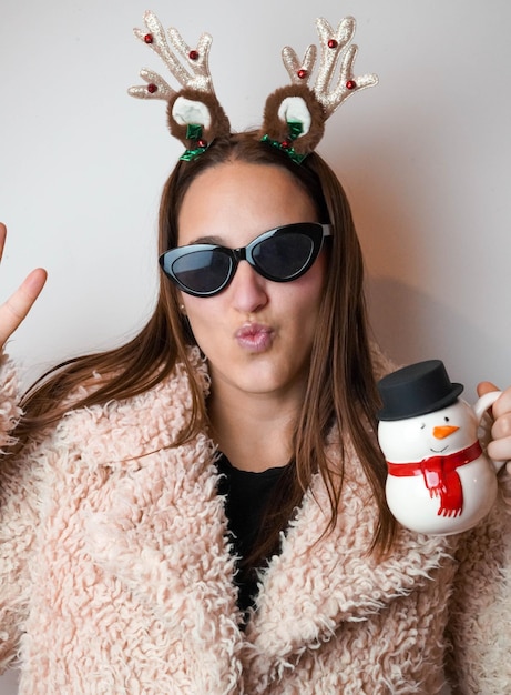 Girl enjoying christmas with a latte and reindeer headband.