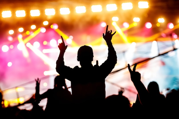 Ragazza che gode di un festival di musica o di un concerto. sagoma nera della folla.