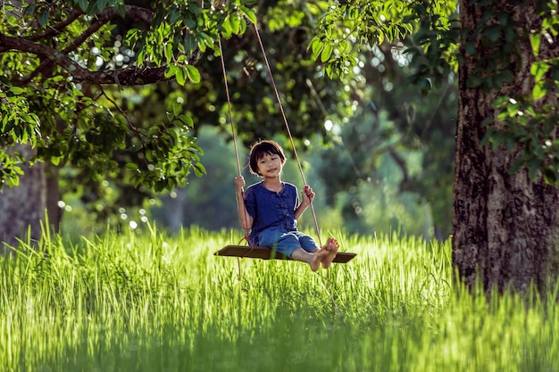 girl enjoying on rope swing in forest