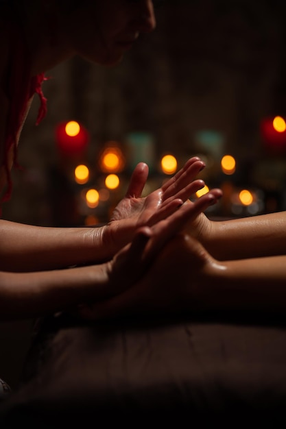 Girl enjoying therapeutic massage with oil in spa with dark lighting, closeup