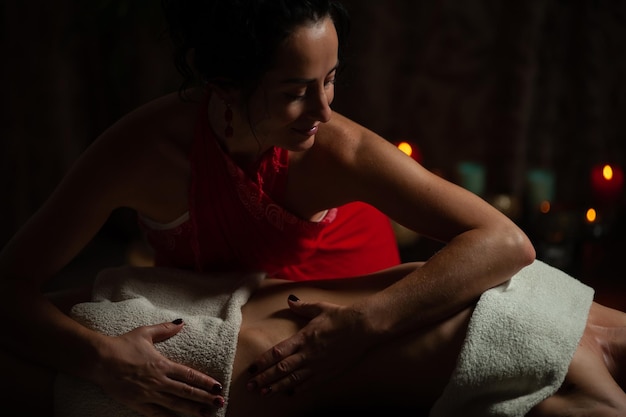 Девушка наслаждается терапевтическим массажем с маслом в спа с темным освещением, крупным планом