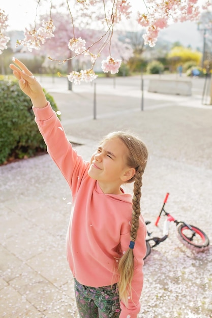 A girl enjoys sakura blossoms while walking through the cherry orchard in spring