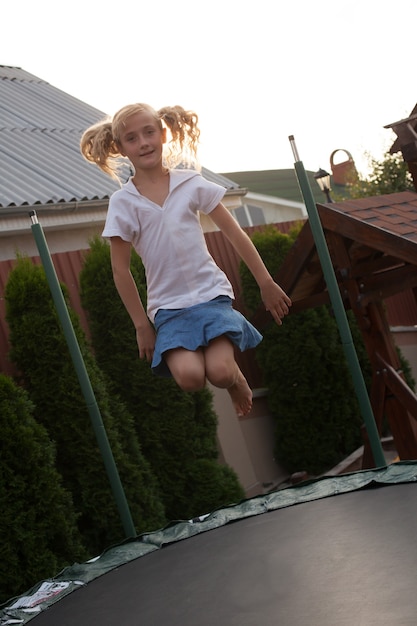 Girl enthusiastically jumping on the trampoline. Moment flight